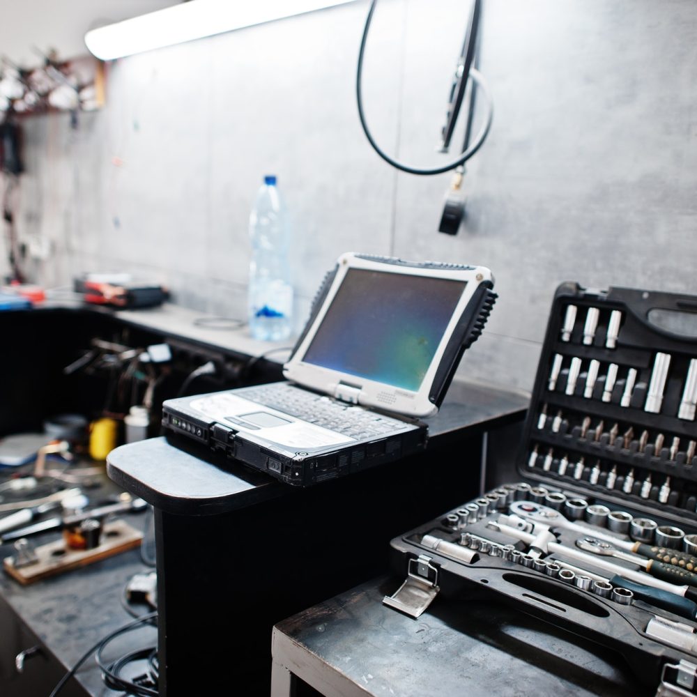 Laptop and tools in maintenance at garage service station.